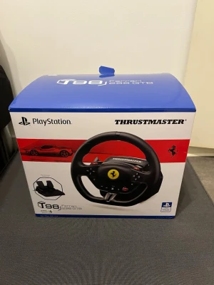 Thrustmaster T80 Ferrari ratt & pedaler - Säljer en Thrustmaster T80 Ferrari 488 GTB ratt och pedalset för PlayStation. Ratten är svart med Ferrari-logga i mitten och har flera knappar för spelkontroll. Pedalerna är också svarta och har halkskyddad yta. Perfekt för racing och bilspel.