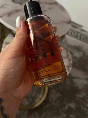 FAME parfym från Paco Rabanne 180ml - FAME parfym från Paco Rabanne i en genomskinlig cylinderformad flaska med svart lock. Vätskan är bärnstensfärgad och flaskan har tryckt svart text och illustrationer. En modern och trendig doft för dig som gillar exklusiva parfymer.