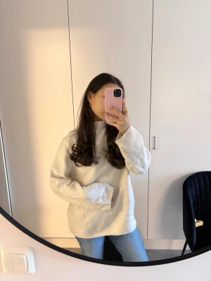 Vit stickad tröja med hög krage - Säljer en enkel och stilren vit stickad tröja med hög ribbad krage. Tröjan har en avslappnad passform och långa ärmar, perfekt för lager på lager. Materialet känns mjukt och bekvämt mot huden. Passar till jeans eller kjol för en clean look.