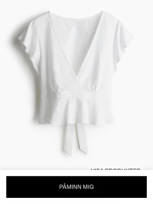 Vit omlottopp med knyt i midjan - Snygg vit omlottopp med v-ringning i storlek XS. Toppen har ett knytband i midjan och lätt volang nedtill.  Säljer pga för liten