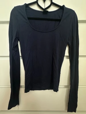 Mörkblå långärmad topp - En enkel och stilren mörkblå långärmad topp med rund halsringning och med slit i ärmarna. Tillverkad i mjukt material som sitter skönt mot kroppen. 
