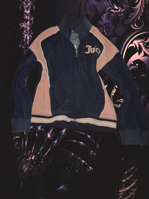 Juicy Couture zip hoodie i navy och rosa - Säljer en snygg zip hoodie från Juicy Couture i navyblått med ljusrosa paneler och broderad logga på bröstet. Hoodien har dragkedja framtill, ribbade muddar och sportig design. Perfekt för dig som gillar klassisk Y2K-stil.