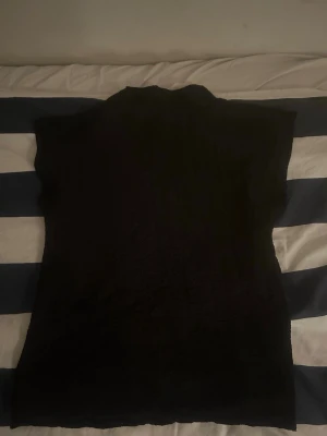 Svart polotopp i ribbad stil - Snygg svart polotopp med ribbad struktur. Helt som by aldrig använd. 