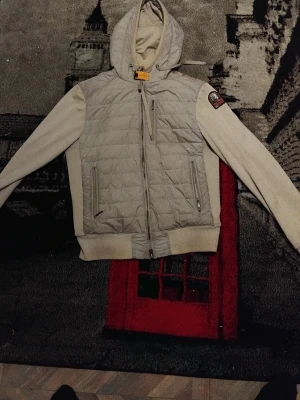 Beige quiltad jacka från Parajumpers - Snygg beige jacka från Parajumpers med quiltad front, huva och ribbade muddar,ÄKTA. Jackan har dragkedja framtill, två sidofickor med dragkedja och en patch på ärmen. Perfekt för dig som vill ha en stilren och sportig look.Kan tänkas byta