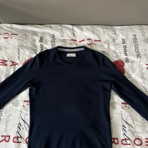 Mörkblå tröja från Pier One - Säljer en stilren mörkblå tröja från Pier One. Tröjan har en v-ringad hals och långa ärmar, perfekt för en klassisk look. Den är tillverkad i ett mjukt material som ger en bekväm passform.