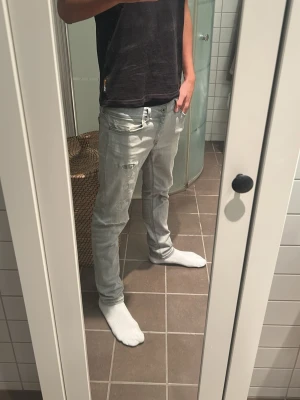 Dondup jeans - Säljer ett par ljusgrå slim fit jeans med slitningar och detaljer på låret. Jeansen har klassisk femficksdesign och normal midja. Perfekta för dig som gillar en avslappnad men ändå trendig stil.