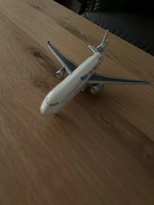 Vit modellflygplan i plast - Säljer ett detaljerat modellflygplan i vit plast med gråa vingar och små dekaler på kroppen. Perfekt som prydnad eller för samlare av flygplansmodeller. Modellen har tre motorer och realistiska detaljer på vingarna.