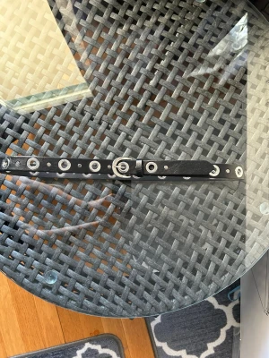 Svart bälte med silverringar - Snyggt svart bälte med stora silverfärgade metallringar längs hela bandet. Perfekt accessoar för att ge din outfit en edgy vibe. Bältet har ett klassiskt spänne i silver och är gjort i skinnimitation.