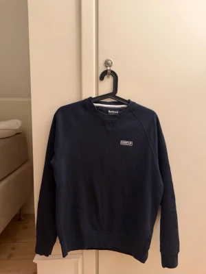 Mörkblå sweatshirt från Barbour - Säljer tröjan pågrund av att jag har börjat växa ur den, jag är 1,85cm och den är nästintill kort. Tröjan är i jätte fint skick.