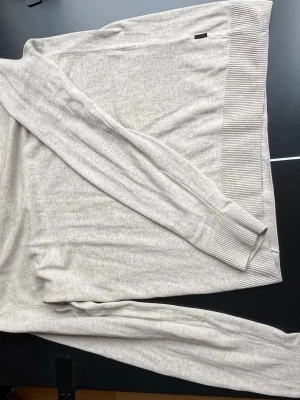 Beige stickad tröja Jack & Jones - Beige stickad tröja från Jack & Jones med långa ärmar och ribbade muddar samt nederkant. Enkel och stilren design som passar perfekt till jeans eller chinos. Mjuk och skön kvalitet, perfekt för lager-på-lager.