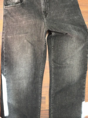 Svarta raka jeans - Säljer ett par svarta jeans med rak passform och klassisk femficksdesign. Jeansen har en lätt tvättad look och är tillverkade i denim. Perfekta för dig som gillar en enkel och stilren stil.