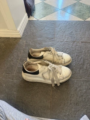 Vita sneakers med svart detalj - Säljer ett par alexander mcqueen sneakers, de är väl använda men går att tvätta för att se lite fräschare ut. 
