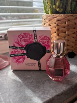 Viktor & Rolf Flowerbomb Pretty Peony - En lyxig parfym från Viktor & Rolf, Flowerbomb Pretty Peony. Flaskan är rosa och har en multifacetterad design med silverfärgad kork. Doften är blommig och feminin, och förpackningen pryds av rosa pioner. 30ml, ny 