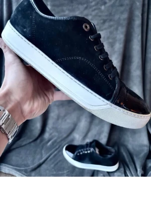 Lanvins - Stilrena svarta lanvins med vit sula och svarta skosnören. Ovandelen är i mockaliknande material med detaljer i blankt skinn på tån och runt snörningen. Passar perfekt till streetwear och casual outfits.
