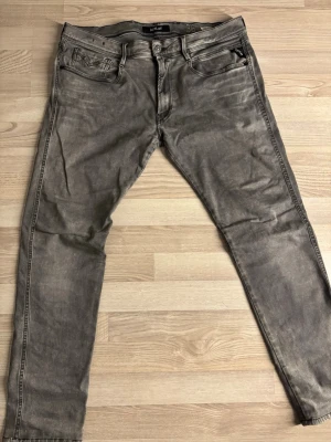 Grå Replay Anbass jeans - Säljer ett par gråa Replay Anbass jeans med snygg tvätt och klassisk femficksmodell. Jeansen har raka ben och detaljerade sömmar. Perfekta för dig som gillar en avslappnad men ändå stilren look. W36 L32