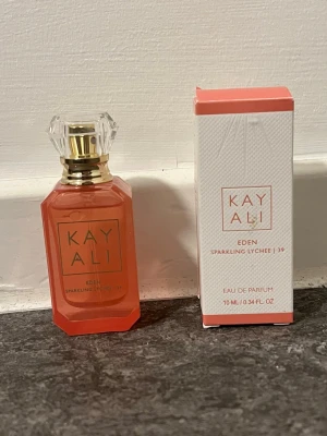 Kayali Eden Sparkling Lychee 10ml - Endast testad en gång! Kayali Eden Sparkling Lychee Eau de Parfum. Doften är fruktig, söt och fräsch med inslag av vanilj, tropiska och blommiga toner. Flaskan rymmer 10 ml och kommer i originalförpackning. Original pris: 379:-