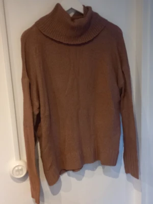 Lila polotröja från 157 - Mysig Lila stickad polotröja från 157 med bred krage och långa ärmar. Tröjan har en avslappnad passform och ribbstickade detaljer vid krage och ärmslut. Perfekt för kalla dagar och enkel att matcha med jeans eller kjol.