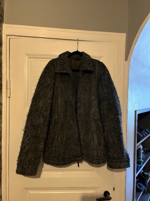 Grå pälsjacka från Welter Shelter - Säljer en grå pälsjacka från Welter Shelter med fluffig, långhårig yta och klassisk krage. Jackan har dragkedja framtill och är fodrad på insidan för extra värme. Perfekt för kalla dagar när du vill ha både stil och komfort.