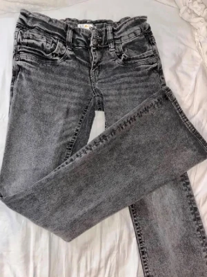 Grå bootcut jeans med tvättad look - Snygga grå jeans med bootcut passform och tvättad finish. Klassisk femficksmodell med bälteshällor och dragkedjegylf. Perfekta för en avslappnad och trendig stil.