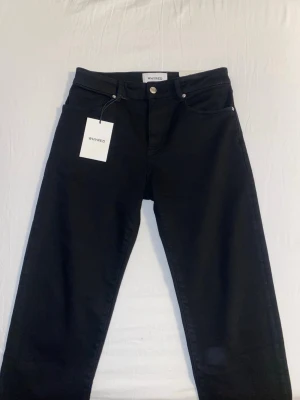 Svarta slim fit jeans från Whyred - Snygga svarta slim fit jeans från Whyred med klassisk femficksmodell och raka ben. Jeansen har en stilren look med silverfärgade nitar och knapp, samt bälteshällor. Perfekta för dig som gillar minimalistisk och modern stil.