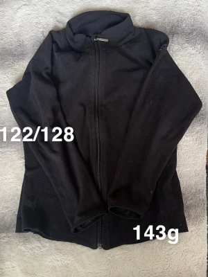 Svart fleecejacka med dragkedja - svart fleecejacka med hel dragkedja framtill och hög krage. Perfekt som mellanlager under kyliga dagar. Långärmad och enkel design som passar till det mesta.🌸 Fint använt skicj. Storlek 122/128