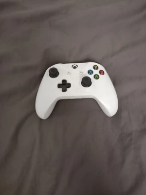 Vit Xbox Series X/S handkontroll - Säljer en vit trådlös handkontroll till Xbox Series X/S. Kontrollern har klassisk Xbox-design med svarta styrspakar, D-pad och färgade knappar. Tillverkad i plast och passar perfekt för gaming på konsol eller PC.