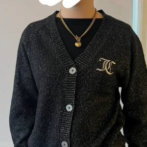 Svart glittrig kofta från juicy couture  - Säljer en svart glittrig kofta från juicy couture med stora knappar och broderad logga på bröstet. Knappt använd.