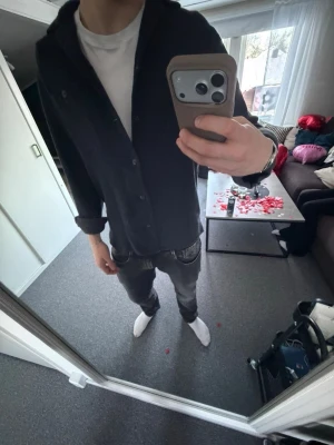 Svart overshirt med klassisk passform - Säljer en svart overshirt med klassisk rak passform och knäppning framtill. Jackan har långa ärmar, enkel krage och diskreta sömmar. Perfekt för dig som gillar en stilren och enkel look. Passar till det mesta och är lätt att matcha.