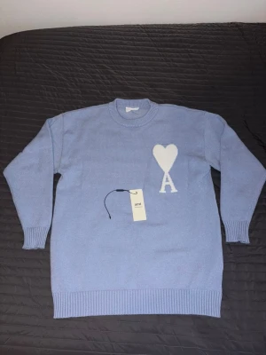 Ljusblå stickad tröja från Ami Paris  - Ljusblå stickad tröja från Ami Paris, vill sälja tröja nu för att den ej passar längre har använt det en/två gånger. Om ni är intresserade så kan jag gör en bra deal😁 (seriösa kunder)