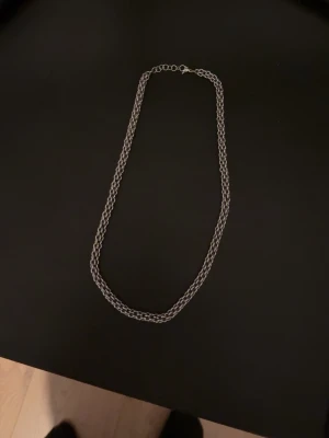 Silverfärgat kedjehalsband - Snyggt halsband i silverfärg med tvinnad kedja. Halsbandet har en enkel och stilren design som passar till många olika looks. Längden kan justeras med hjälp av förlängningskedjan. Perfekt accessoar för att lyfta din outfit.