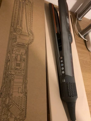 Dyson Airstrait hårstyler grå/koppar med kvitto - Säljer en Dyson Airstrait hårstyler i snygg grå och kopparfärg. Plattången har digitala knappar och en modern design med ventilerade sidor. Perfekt för att styla och torka håret samtidigt. Levereras i originalkartong. Den är helt ny, tar emot rimliga bud