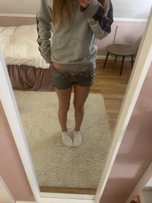 Gråa jeansshorts med rå kant - Säljer ett par gråa denimshorts med råa, fransiga kanter och klassisk femficksdesign. Shortsen har låg midja och slitna detaljer för en avslappnad look. Perfekta för varma dagar och enkel att matcha med olika toppar. Det är storlek 140 i barn storlek 