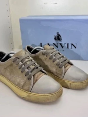 Lanvin beige låga sneakers - Snygga sneakers från Lanvin i beige mocka med gråa skosnören och tåparti i ljusgrått läder. Sulan är gulaktig och ger en cool vintagekänsla. Klassisk låg modell med rund tå och diskret design som passar till det mesta.