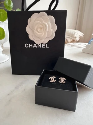 Äkta chanelörhängen - Säljer ett par ikoniska Chanel örhängen i silverfärg med klassiska CC-loggan köpa på Harrods i London finns ej kvar i sortimentet. Kommer i original ask och med tillhörande påse  kvitto och äkthetsbevis. 