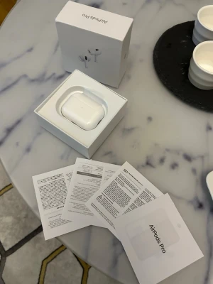 Apple AirPods Pro trådlösa hörlurar - Säljer ett par vita Apple AirPods Pro med laddningsetui. Hörlurarna är trådlösa och levereras i originalförpackning med tillhörande manualer. Snygg och kompakt design i blank plast, perfekt för dig som vill ha grymt ljud och smidig anslutning till din iPhone.
