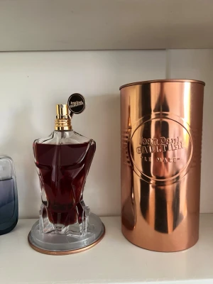 Jean Paul Gaultier Le Male Essence EdP - Jean Paul Gaultier Le Male Essence de Parfum i 125 ml flaska. Flaskan har en unik design i form av en manlig torso i genomskinligt glas med mörkröd vätska och gulddetaljer. Kommer i en metallisk kopparfärgad cylinderförpackning. EXTREMT OVANLIG
