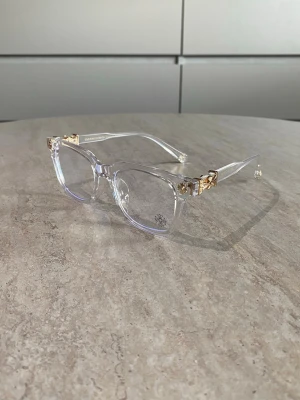 Chrome heart glasögon - Snygga solglasögon från Chrome heart med transparent båge och unika guldfärgade detaljer vid gångjärnen. Anti blue lights. Lätta och bekväma att bära hela dagen.