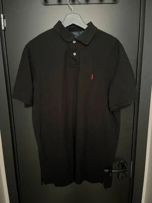Svart pikétröja från Polo Ralph Lauren - Klassisk svart pikétröja från Polo Ralph Lauren.  Skulle säga att den passar bäst för 182+, Inga tecken på användning hör av er vid pris eller andra frågor! Mvh Axel H.