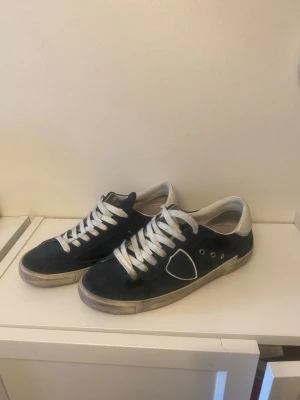 Philippe Model låga sneakers  - Snygga marinblåa sneakers från Philippe Model som knappt är använda. Skorna har en låg siluett, rund tå och en vit sula med slitna detaljer. Materialet är en mix av läder och textil, och sidan pryds av den ikoniska sköld-loggan.