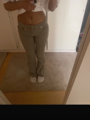 Beige bootcut jeans med låg midja - Snygga beige jeans med bootcut-modell och låg midja. Klassisk femficksdesign och bälteshällor. Jeansen har en enkel look som passar till det mesta och är tillverkade i ett mjukt denimtyg. Perfekta för dig som gillar en avslappnad men trendig stil.