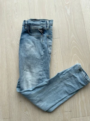Ljusblå jeans från Replay - Säljer ett par ljusblå jeans från Replay med klassisk femficksdesign och snygg tvättad look. Jeansen har raka ben och är tillverkade i mjukt denimtyg som ger en avslappnad vibe. Perfekta för dig som gillar en stilren och enkel look.