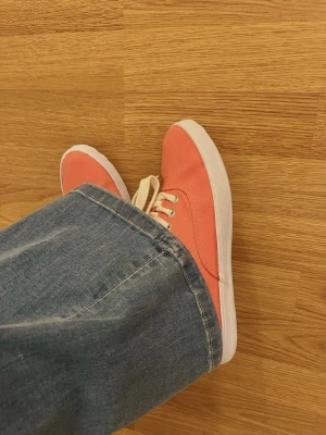 Korallfärgade sneakers med snörning - Säljer ett par fräscha sneakers i en snygg korallfärg med vita snören och vit sula. Perfekta för dig som vill ha lite färg till outfiten!💕Vet tyvärr inte märket! 