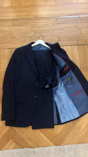 Mörkblått kostymsett från Dressmann - Stilren mörkblått kostymset från Dressmann i modellen Slim Fit. Använd kanske 6 gånger och köpptes ny för ca 3000.  Storleken är 46 på kavajen och 31/32 på byxorna