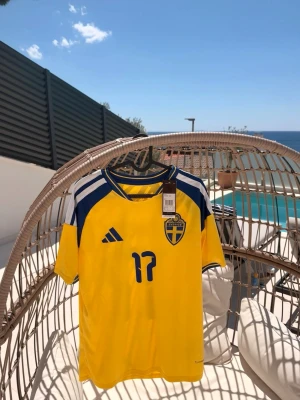 Svensk fotbollströja Adidas gul - Gul fotbollströja med blå detaljer och nummer 17 och Gyökeres på ryggen. Tillverkad i lätt och ventilerande material, perfekt för träning eller match.