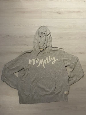 Grå hoodie från Odd Molly - Säljer en ljusgrå hoodie från Odd Molly med stor vit logga över bröstet. Hoodien har huva med dragsko, magficka och ribbade muddar vid ärmslut och nederkant. Tillverkad i mjukt material som känns skönt mot huden. Perfekt för en avslappnad och trendig look.