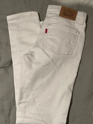 Vita jeans från Levi's - Snygga vita jeans från Levi's med klassisk femficksdesign och ikonisk läderpatch bak. Jeansen har raka ben och är tillverkade i bomull. Perfekta för en clean och fräsch look.