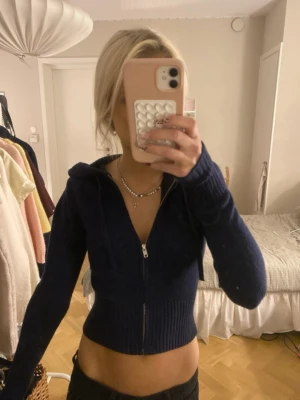 Mörkblå croppad hoodie med dragkedja - Säljer en mörkblå croppad hoodie med dragkedja framtill och huva med dragsko. Hoodien har långa ärmar och bred ribbad mudd vid midjan och ärmsluten. Andvänd 1 gång så jättebra skick