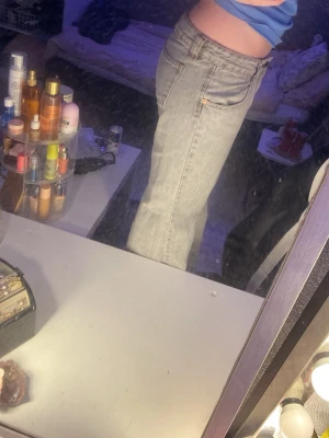 Ljusgrå raka jeans med hög midja - Säljer ett par ljusgrå jeans med raka ben och hög midja. Jeansen har klassiska fem fickor och gylf med knapp. Perfekta för en avslappnad och trendig look. Materialet känns som bomull med lite stretch. (Dom är stora i storlek) 