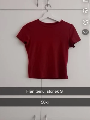 Mörkröd croppad topp från Temu - En enkel och stilren mörkröd croppad topp från Temu. Toppen har rund halsringning och korta ärmar, perfekt att matcha med höga jeans eller kjol. Materialet känns mjukt och stretchigt.