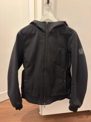 Belstaff jacka  - Säljer en riktigt snygg svart Belstaff jacka i storlek 46. Stilren design med bra passform och skönt material – funkar lika bra till vardags som lite mer uppklätt.  Jackan är i fint skick och har knappt använts, inga större slitningar eller skador. Dragkedjor och detaljer är hela och funkar som de ska.  Tyvärr inget kvitto kvar, men äkta vara med tydliga Belstaff-detaljer.  Hör av dig vid frågor eller om du vill ha fler bilder!
